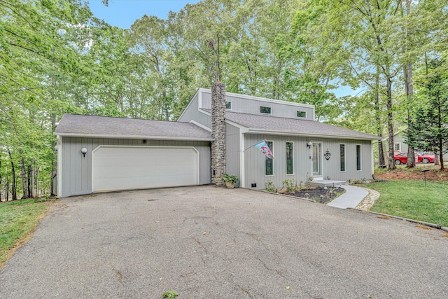 view of front of home with roof with shingles, a garage, a front lawn, and aphalt driveway