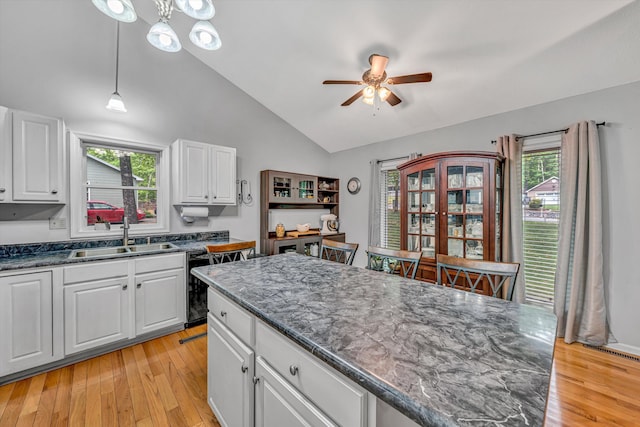 kitchen with a ceiling fan, white cabinetry, a sink, lofted ceiling, and light wood-style flooring
