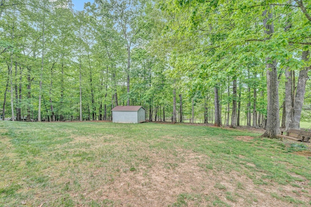 view of yard with a storage shed, an outdoor structure, and a wooded view