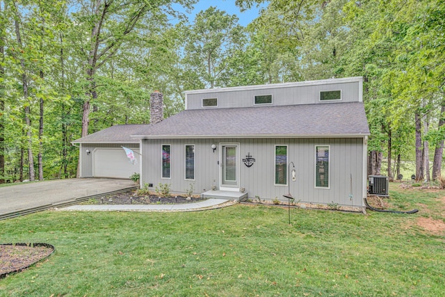 view of front of property featuring roof with shingles, an attached garage, central AC, a chimney, and driveway