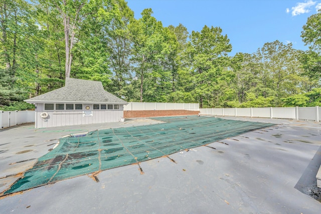 community pool featuring fence, an outdoor structure, and a patio area