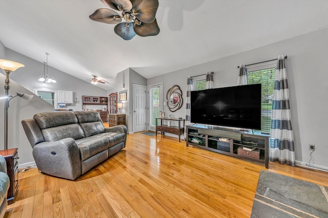 living area with light wood-type flooring, a ceiling fan, a healthy amount of sunlight, and vaulted ceiling