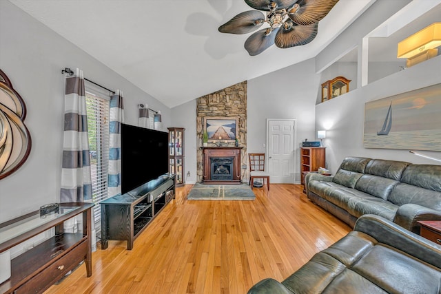 living room featuring a stone fireplace, ceiling fan, hardwood / wood-style floors, and high vaulted ceiling