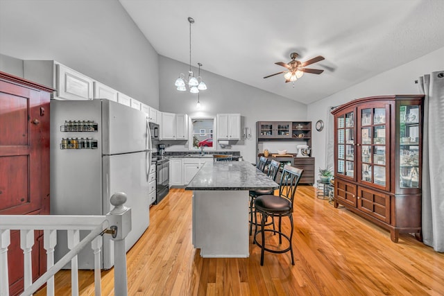 kitchen with freestanding refrigerator, a ceiling fan, white cabinetry, a sink, and black / electric stove