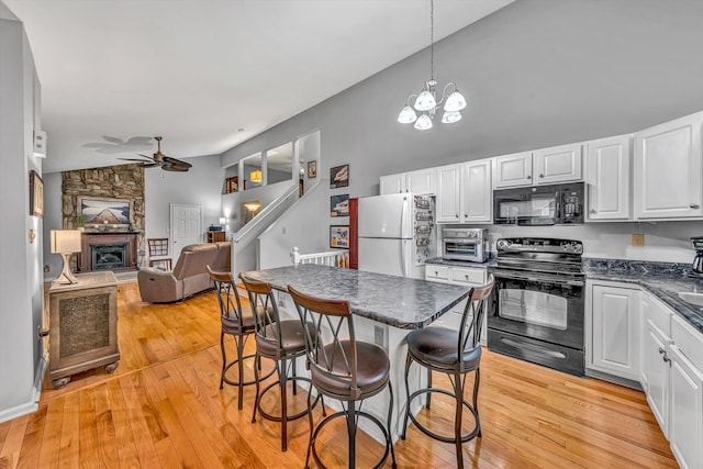 kitchen featuring ceiling fan with notable chandelier, white cabinets, black appliances, and open floor plan