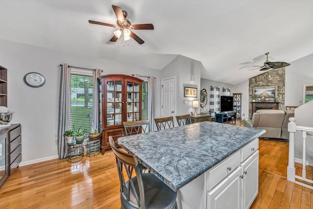 kitchen featuring a kitchen island, a ceiling fan, vaulted ceiling, white cabinetry, and light wood-style flooring