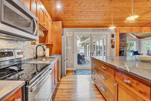 511 Autumn Ave, Huddleston, VA 24104 - kitchen featuring appliances with stainless steel finishes, light wood-type flooring, brown cabinetry, a sink, and backsplash