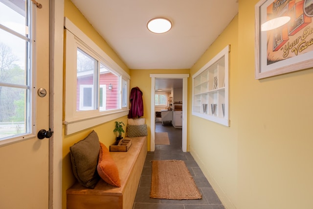 hall featuring dark tile patterned floors and baseboards