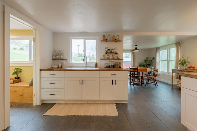 kitchen featuring a sink, white cabinets, open shelves, and dark wood-style flooring