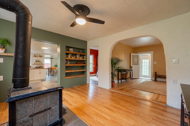 interior space with a healthy amount of sunlight, a ceiling fan, built in features, and arched walkways