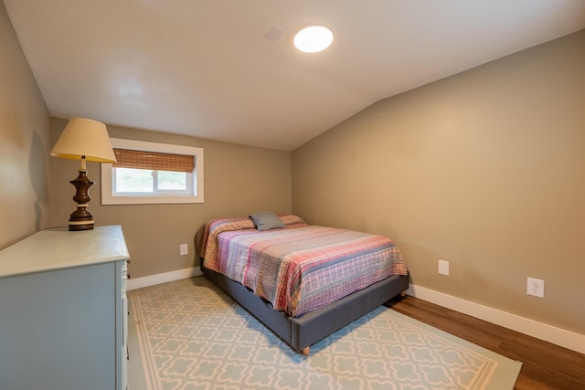 bedroom featuring lofted ceiling, light wood-type flooring, and baseboards