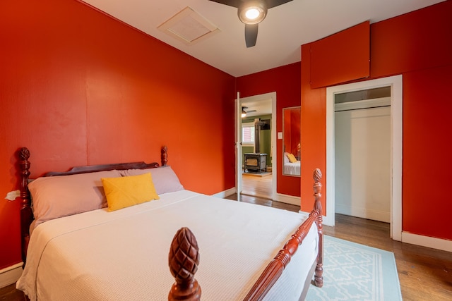 bedroom with baseboards, wood finished floors, a ceiling fan, and attic access