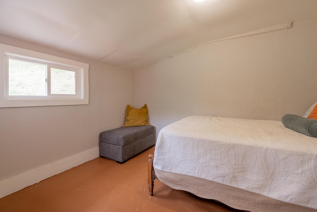 bedroom featuring baseboards, vaulted ceiling, and finished concrete floors