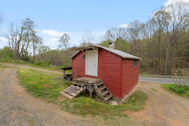 view of outdoor structure with driveway and a view of trees