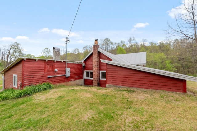 rear view of property featuring a chimney and a yard