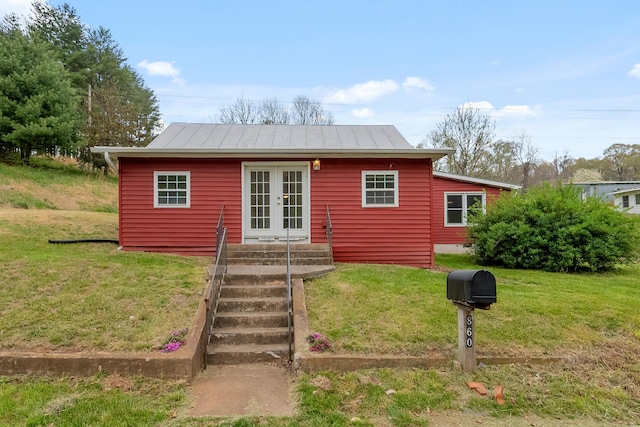 view of front of property featuring a front lawn, a standing seam roof, metal roof, entry steps, and french doors