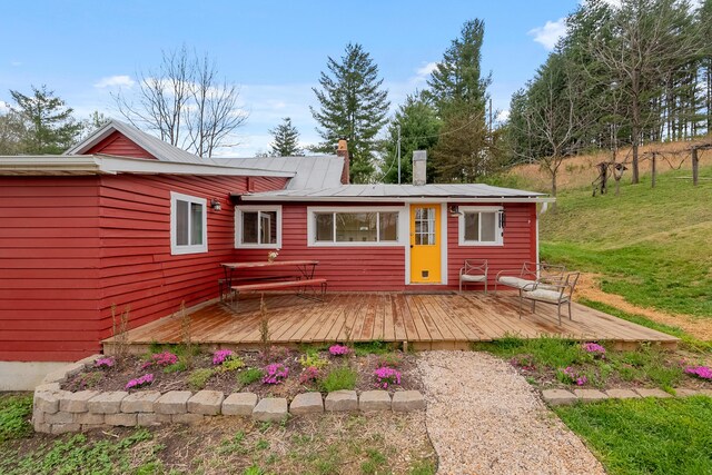 rear view of house featuring a lawn, a chimney, and a deck