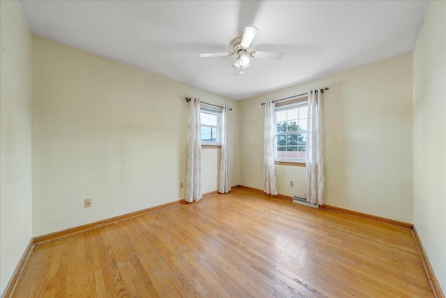 empty room with baseboards, light wood finished floors, ceiling fan, and visible vents