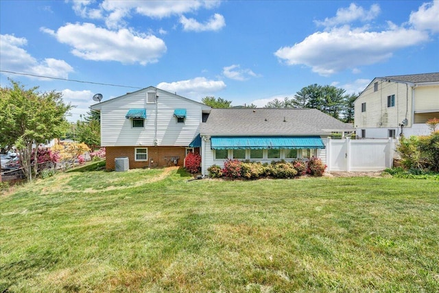 back of house featuring a yard, brick siding, central AC, and fence