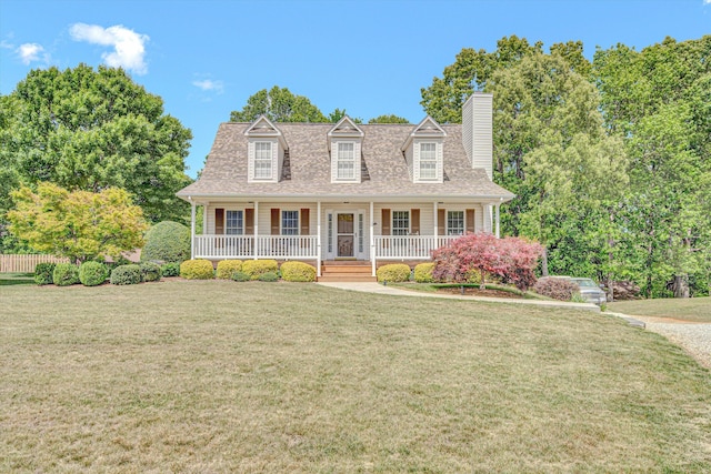 new england style home featuring a shingled roof, covered porch, a chimney, and a front lawn