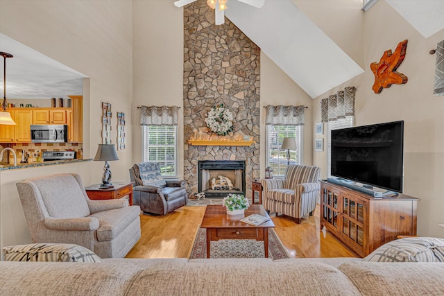 living room featuring a ceiling fan, high vaulted ceiling, a healthy amount of sunlight, and light wood-style flooring