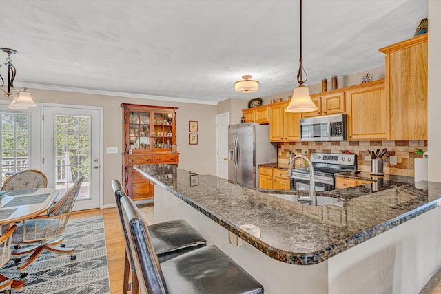 kitchen featuring decorative backsplash, a peninsula, a sink, dark stone countertops, and stainless steel appliances