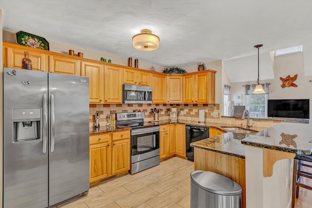 kitchen with backsplash, a sink, dark stone countertops, a peninsula, and stainless steel appliances