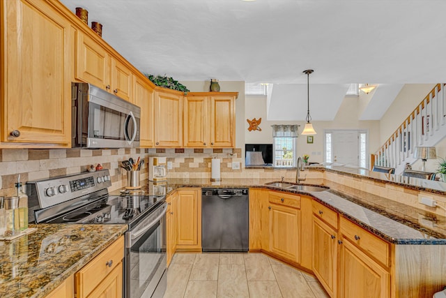 kitchen featuring a sink, appliances with stainless steel finishes, backsplash, and a peninsula