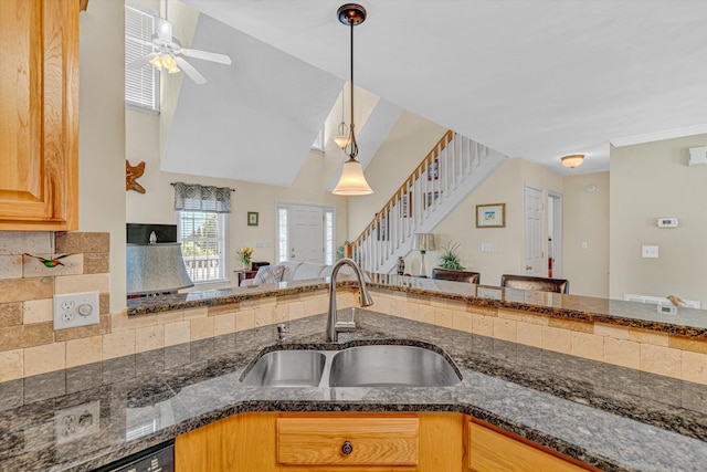 kitchen featuring a sink, dark stone counters, a ceiling fan, open floor plan, and pendant lighting