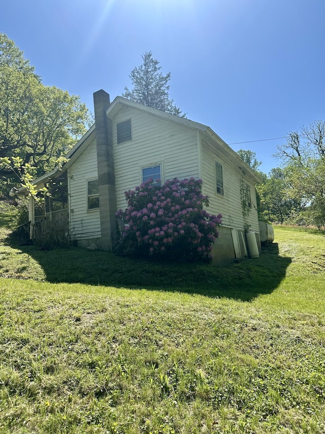 view of side of home featuring a chimney and a yard