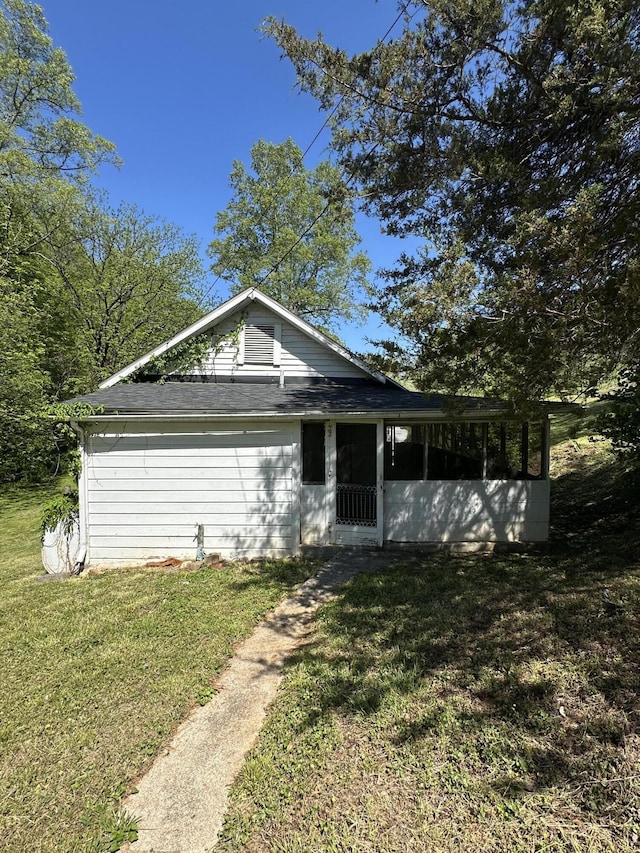 bungalow-style house featuring roof with shingles, a front lawn, and a sunroom