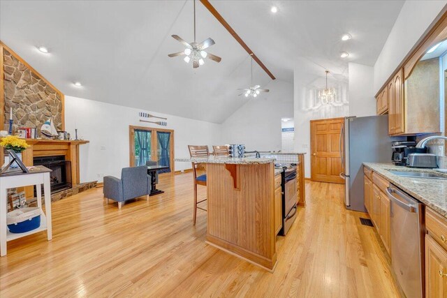 1165 Joffrey Dr, Huddleston, VA 24104 - kitchen with stainless steel appliances, a sink, a kitchen bar, a large fireplace, and light wood finished floors
