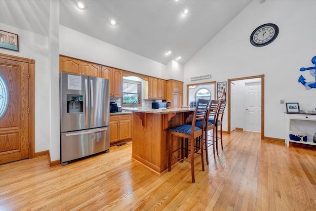 1165 Joffrey Dr, Huddleston, VA 24104 - kitchen with stainless steel fridge, a breakfast bar area, high vaulted ceiling, light wood-type flooring, and light stone counters