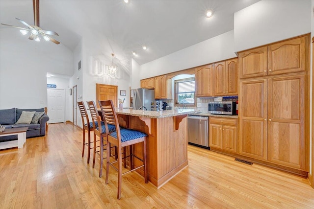 1165 Joffrey Dr, Huddleston, VA 24104 - kitchen with stainless steel appliances, high vaulted ceiling, a breakfast bar, a ceiling fan, and light wood-type flooring