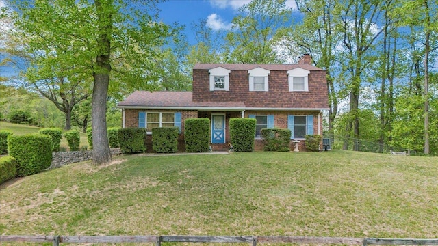 dutch colonial with a front lawn, fence, a chimney, brick siding, and a shingled roof