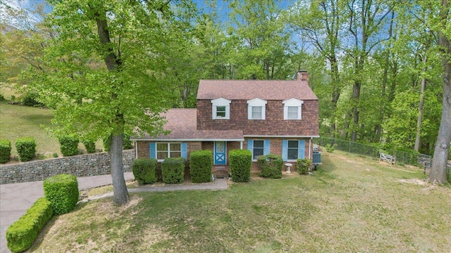 dutch colonial with a front lawn, roof with shingles, fence, and a chimney
