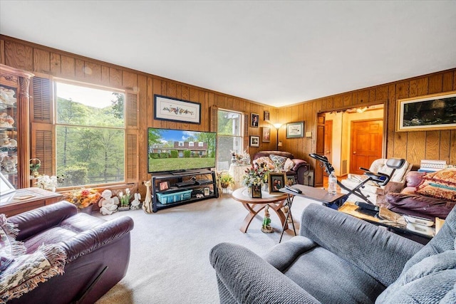 carpeted living area featuring wood walls