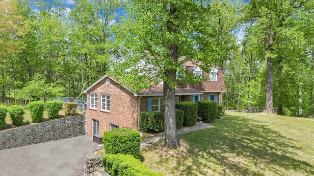 view of home's exterior featuring a lawn, brick siding, and driveway
