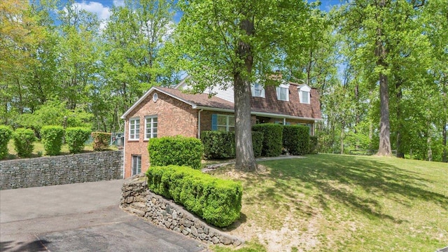 view of home's exterior with a yard, aphalt driveway, and brick siding