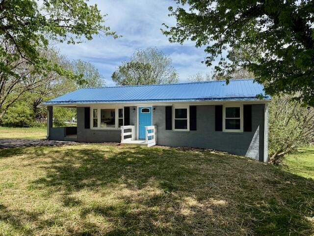 view of front of home with metal roof and a front lawn
