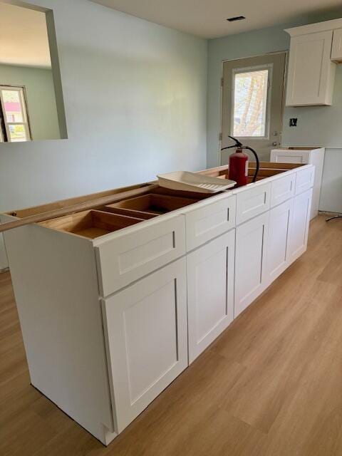 kitchen with light wood finished floors, white cabinetry, and a healthy amount of sunlight