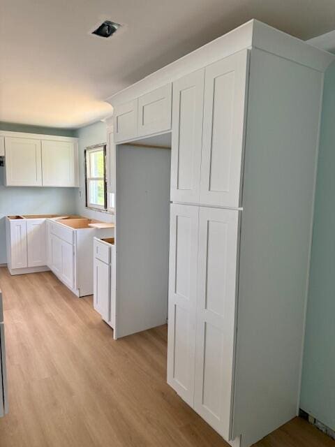 kitchen with white cabinetry, light countertops, and light wood finished floors