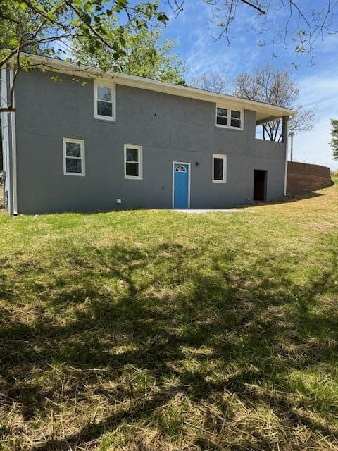 rear view of property with stucco siding and a lawn