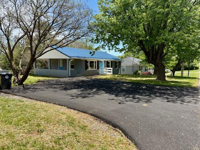 view of front facade with metal roof, a front lawn, and driveway