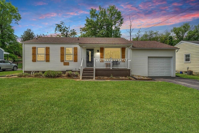 ranch-style house featuring roof with shingles, aphalt driveway, a garage, a front yard, and covered porch