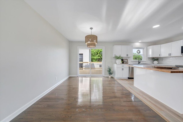 kitchen with wood finished floors, wood counters, dishwasher, and white cabinets