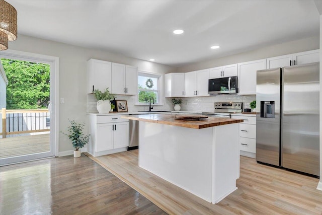 kitchen with appliances with stainless steel finishes, wooden counters, a sink, and tasteful backsplash