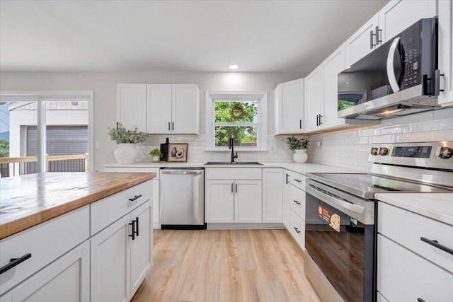 kitchen featuring a sink, appliances with stainless steel finishes, decorative backsplash, and light wood-style floors