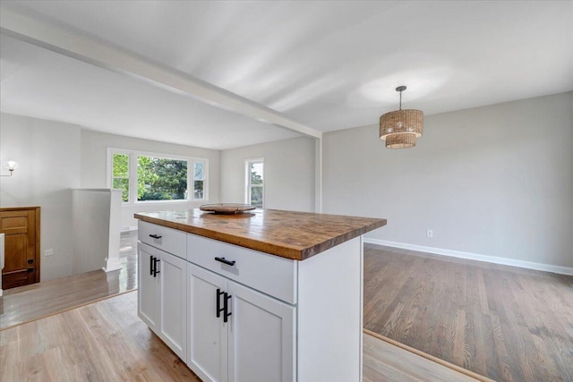 kitchen featuring white cabinets, hanging light fixtures, butcher block countertops, light wood-style flooring, and a center island