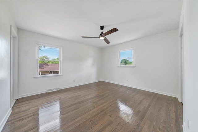 spare room featuring baseboards, ceiling fan, visible vents, and wood finished floors